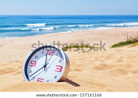 Classic analog clocks in the sand on the beach near the sea. For the holidays. Royalty-Free Stock Photo #137161166