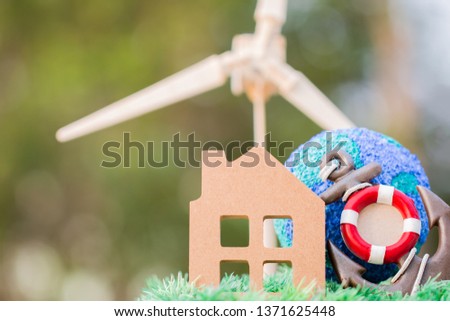 Insurance services / loan debt Property House protection, Green Energy/Future Alternative energy or awareness of environment concept. Home on red lifebuoy anchor and Wind turbine /Wind mill with home.