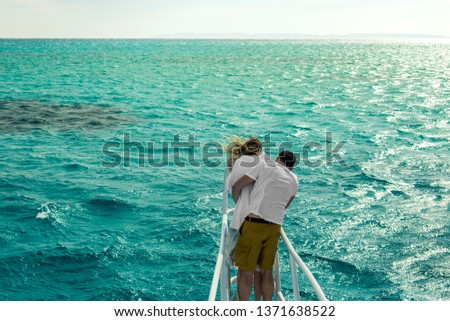 couple is hugging on the bow of the yacht against the blue sea