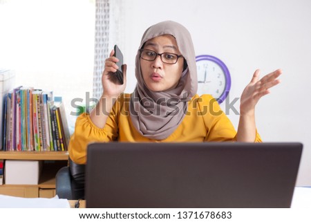 Portrait of busy muslim businesswoman working in office, multi tasking worker, woman talking on phone 