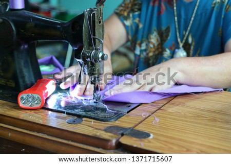Close-up picture of an elderly seamstress, sewing woman  Clothing design  Old model sewing machine, hobby is a small business at home.