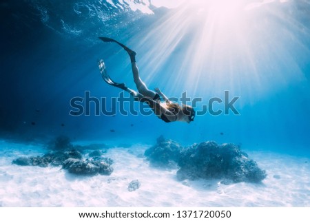 Woman freediver glides with fins. over sandy sea. Freediving and beautiful light in blue ocean Royalty-Free Stock Photo #1371720050
