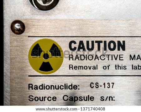 Radiation warning sign on the nameplate and the machanical container of factory process instrument, Ionizing radiation hazard symbol as background