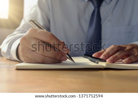 Close-up pictures of a man who wrote a spiral notebook on the table with a coffee mug and writer's idea.