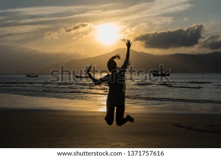 Silhouette of a girl jumping in the beach during sunset