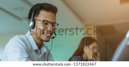 close up call center latin man wear headset for talking with customer and working with asian employee colleague woman at operation room , help desk support concept Royalty-Free Stock Photo #1371822467