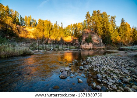 beautiful golden sunrise over forest river with sandstone cliffs on the shores. stormy water