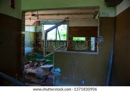 old abandoned farmhouse interior in green summer bushes