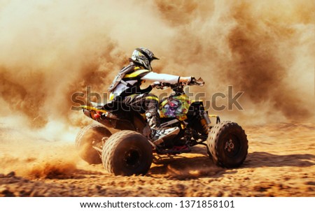 Quad bike in dust cloud, sand quarry on background. ATV Rider in the action.