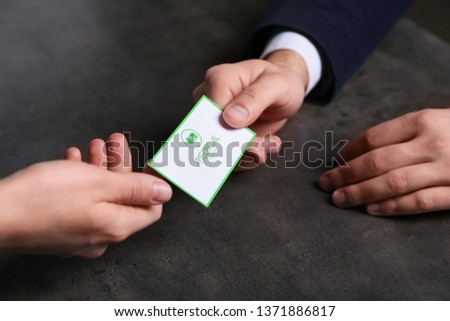 Man giving medical business card to woman on dark background, closeup. Nephrology service