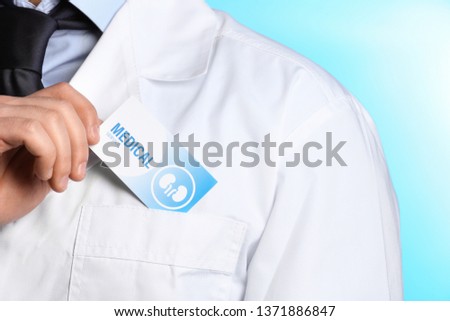 Doctor putting business card into pocket on color background, closeup. Medical service