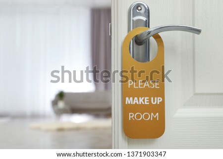 Open door with sign PLEASE MAKE UP ROOM on handle at hotel, space for text
