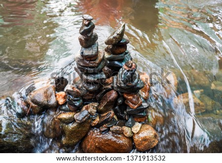 The stones are arranged together in a tower in the water.