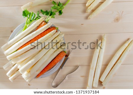 New harvest of white asparagus, high quality raw asparagus, carrot and selery on board in spring season, ready to cook close up