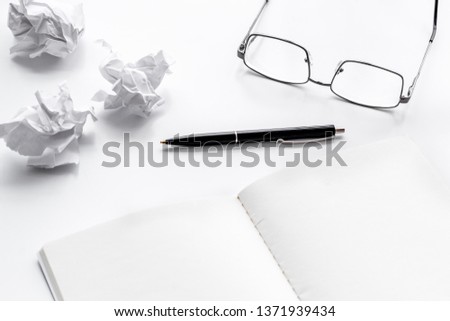 blogger office desk with glasses, notebook, pen and paper balls on white background copyspace