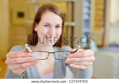 Young woman holding new glasses in optician store Royalty-Free Stock Photo #137194703