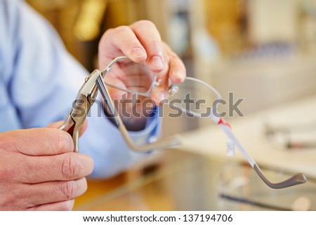 Hand of optician fixing glasses with bending pliers Royalty-Free Stock Photo #137194706