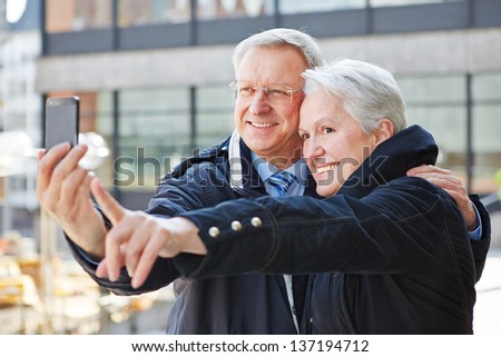 Two happy senior people taking photos with a smartphone