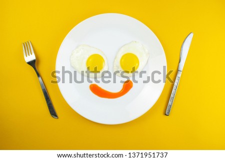 traditional breakfast of two fried eggs. Fun face from food. Plate with eggs on a yellow background. Concept image of breakfast, healthy eating.