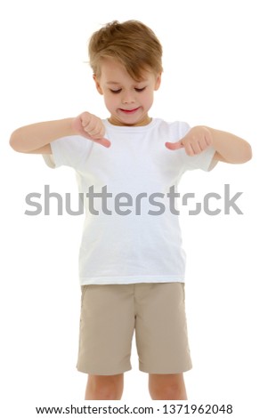 A cute little boy in a pure white T-shirt points his fingers at her. On a T-shirt, you can make an advertising inscription or picture. The concept of promoting children's products. Isolated on white
