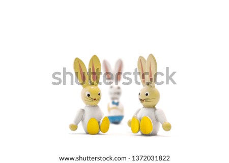 Two toy easter bunnies sitting side by side with their father in the background. Single parent family. Landscape format.