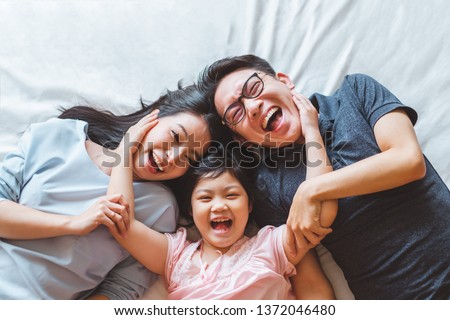 Happy Asian family laying on bed in bedroom with happy and smile, top view Royalty-Free Stock Photo #1372046480