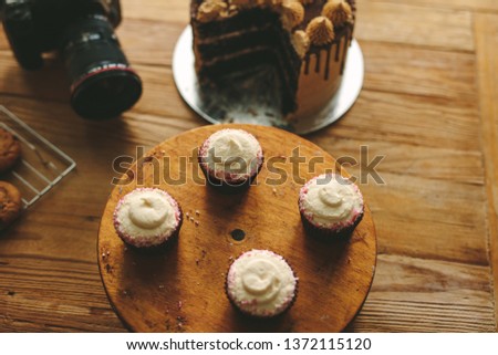 Top view of freshly made cupcake and a cakes on wooden table with a professional camera. Dessert with dslr camera on kitchen counter.