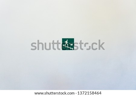 green sign evacuation stairs on a white wall in a bright room