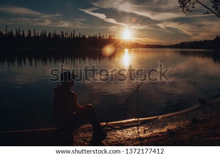 Fishing. Silhouette of a fisherman. Fisherman catches fish at sunset on the river