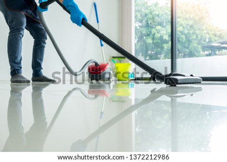 Young attractive man is cleaning vacuum commercial cleaning equipment on floor at home helping wife Royalty-Free Stock Photo #1372212986