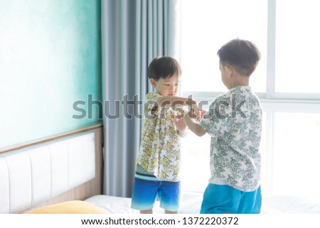 2 cute brothers are taking a picture each other the morning on the bed.