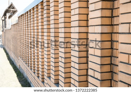 View of the fence made of sand-colored bricks with a perspective on a clear Sunny day. Construction, interior design, technology.