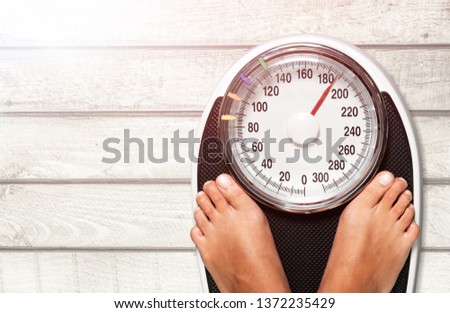 Female legs on scales on background Royalty-Free Stock Photo #1372235429