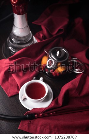 Fruit red tea with berries in glass cup, on table, on red background.Process brewing tea,tea ceremony,Cup of freshly brewed fruit and herbal tea, 
