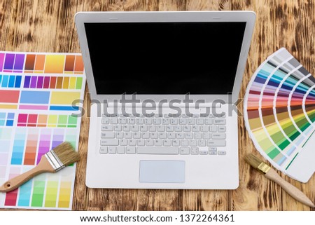 Laptop with color swatches on wooden table for home renovation