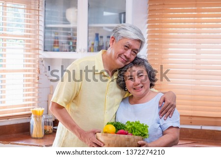 Portrait happiness asian senior couple  at kitchen with a bowl of fresh salad and looking at camera,aging at home conept.