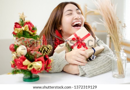 Young asian woman with gift box, birthday or Valentines Day party. Beautiful smiling girl embraces with Christmas gift. Department store is having an Christmas sale. Girl satisfied with shopping gift