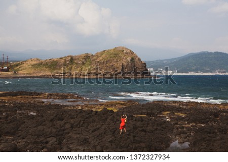 A woman in Jeju Island is holding an eco bag and taking pictures of the beach with her smartphone.Vintage. South Korea
