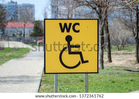 Signboard handicap toilet sign in public park. Restroom for people with disabilities. Pointer with an inscription WC.