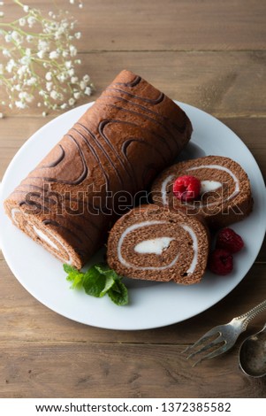 Delicious chocolate roll sponge cake with vanilla cream and mint leaves. Desert sweet food.