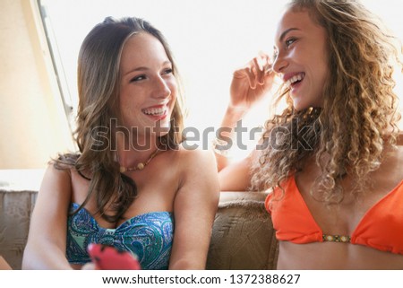 Portrait of beautiful young women relaxing together in caravan interior, smiling laughing on summer beach trip, indoors. Diverse females enjoying discovery travel, leisure recreation lifestyle.