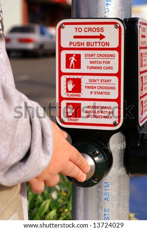Hand pushing a crosswalk button at a traffic signal