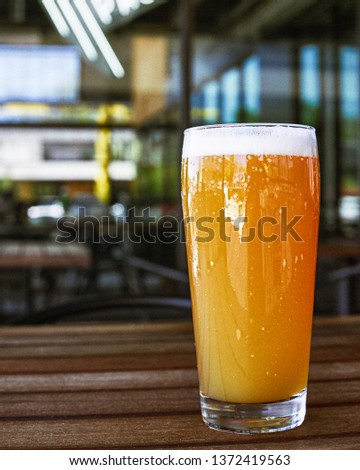Hazy IPA Beer on a Restaurant Patio. On a wooden table.