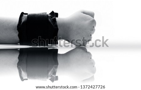 Close up of human hand wearing black colored wrist weights or wrist bands isolated on white along with its reflection.
