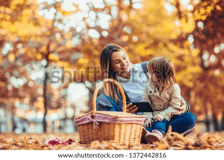 Mother and daughter in the park enjoying the beautiful autumn nature.