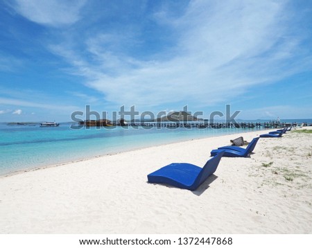 Beautiful view of white sand beach with blue beach bed and wooden bridge in Kanawa island, Indonesia.