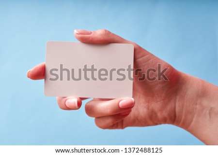 A woman's hand holds a white plastic card. Isolated card in hand.