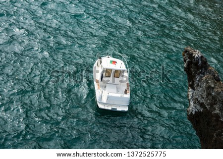 A small white boat is anchored near the shore. Copy space.