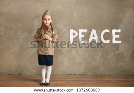 A little girl in uniform with a flower in her hands. The concept of peace on earth.