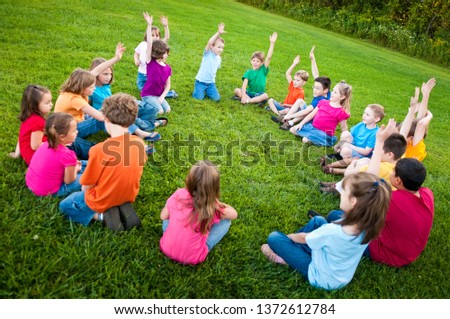 Group of Kids Sitting in a Circle Outside Royalty-Free Stock Photo #1372612784